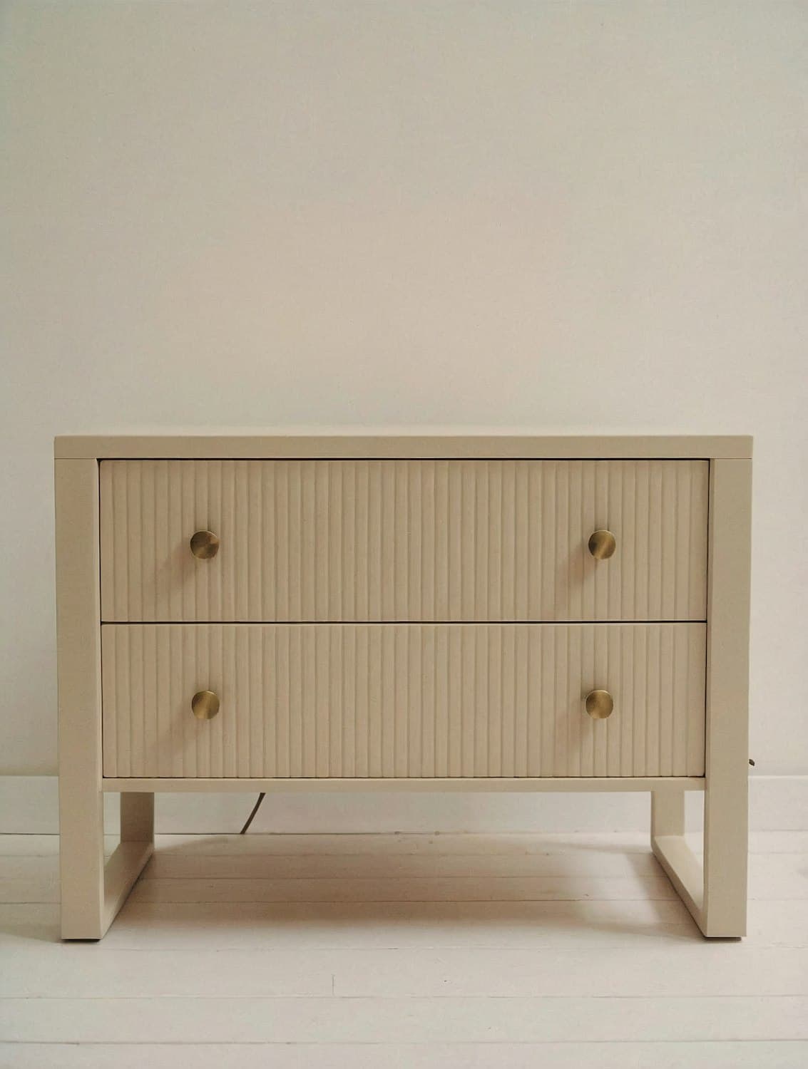 Cream fluted cabinet drawers with round brass knobs